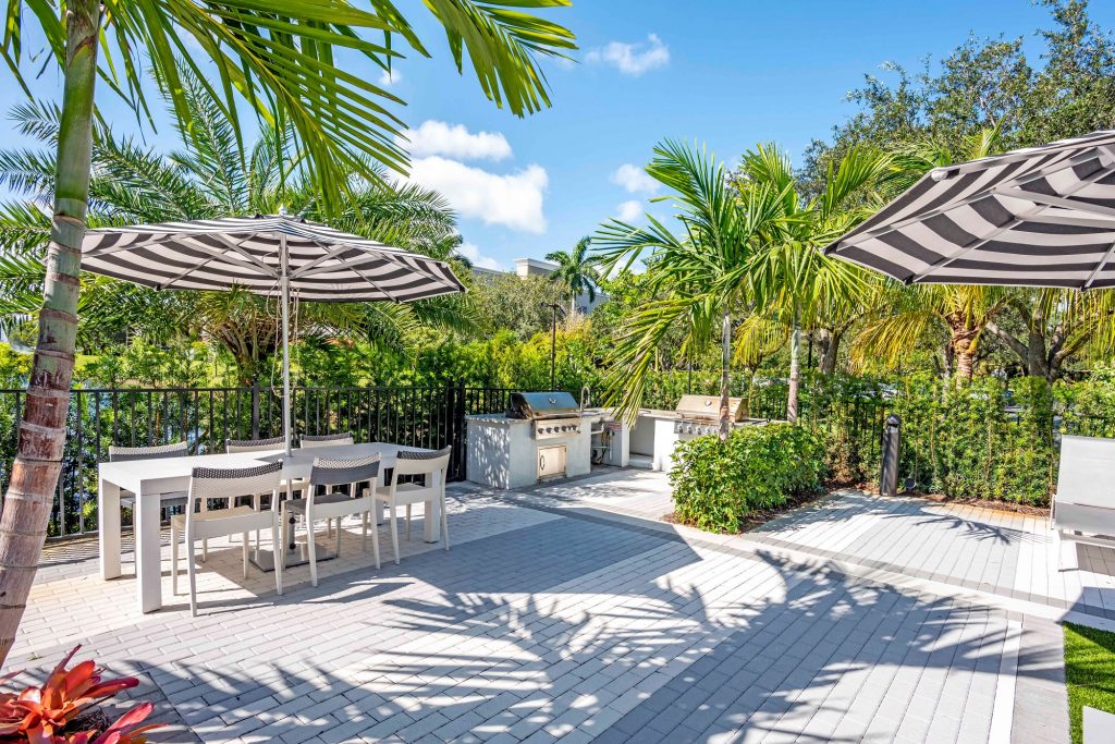 outdoor deck area with shaded seating, grills, and tropical landscaping