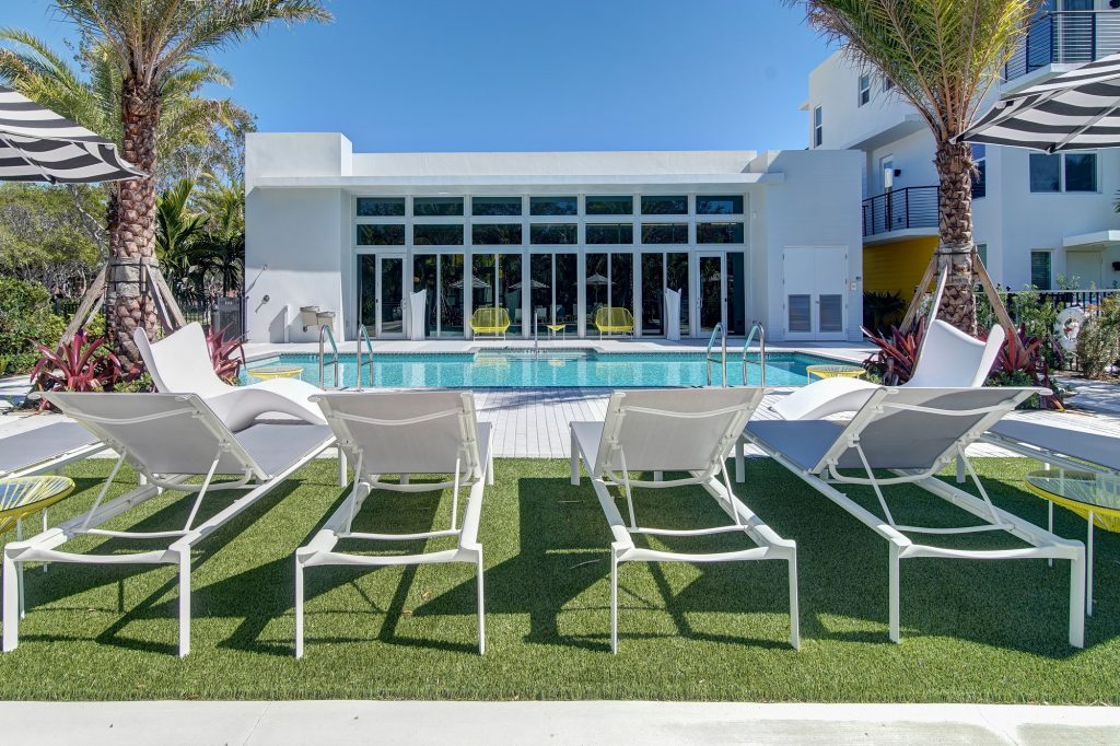 swimming pool deck area with sun tanning beds and tropical landscaping