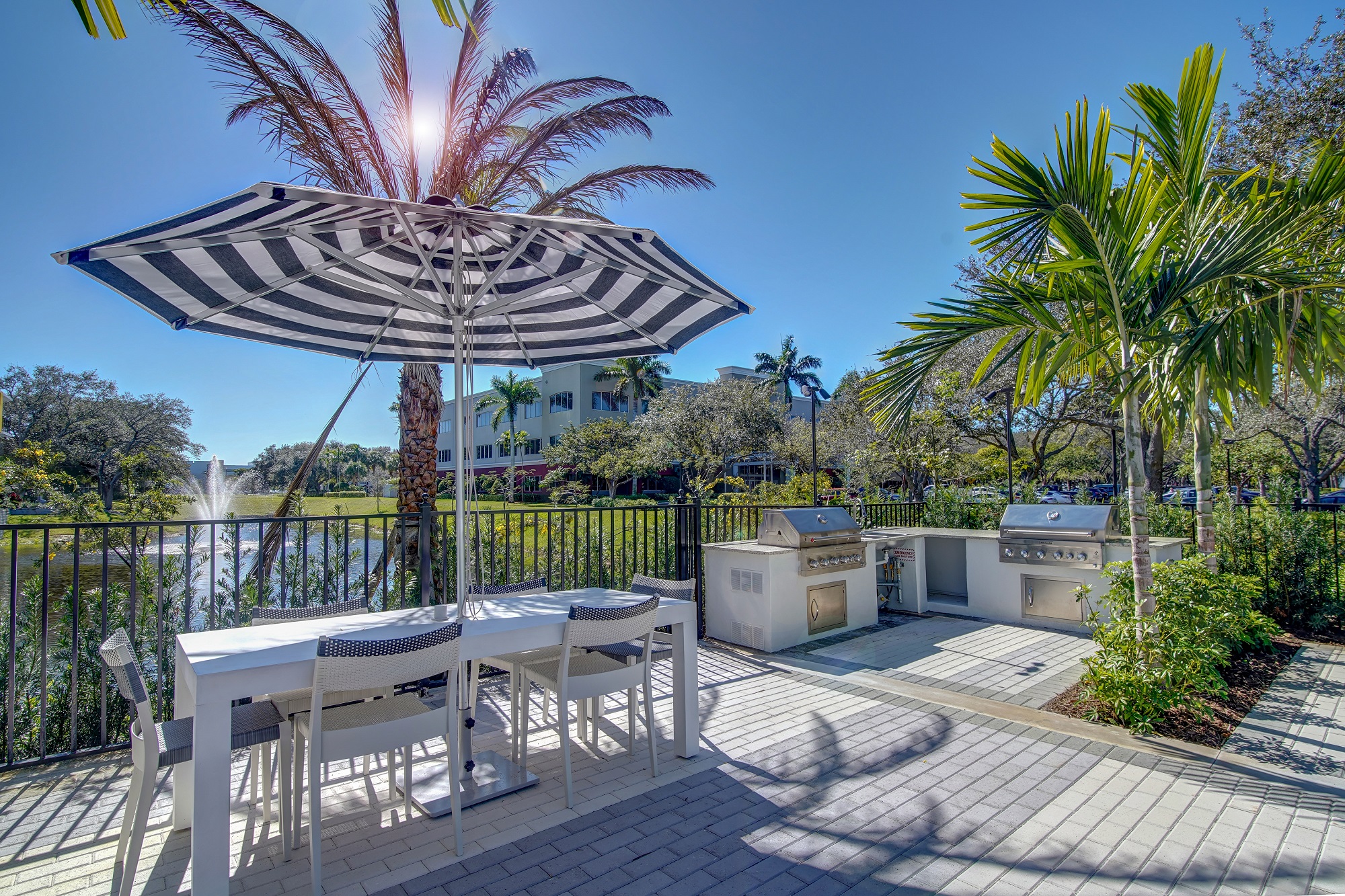 outdoor deck area with shaded seating, grills, and tropical landscaping