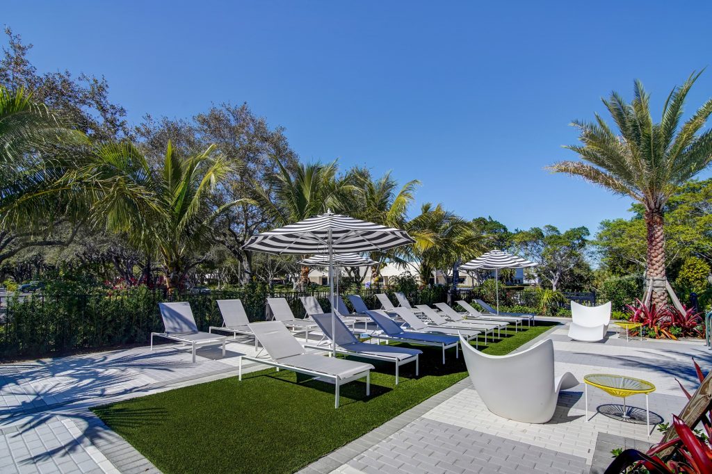 outdoor deck area with shaded seating, grills, and tropical landscaping