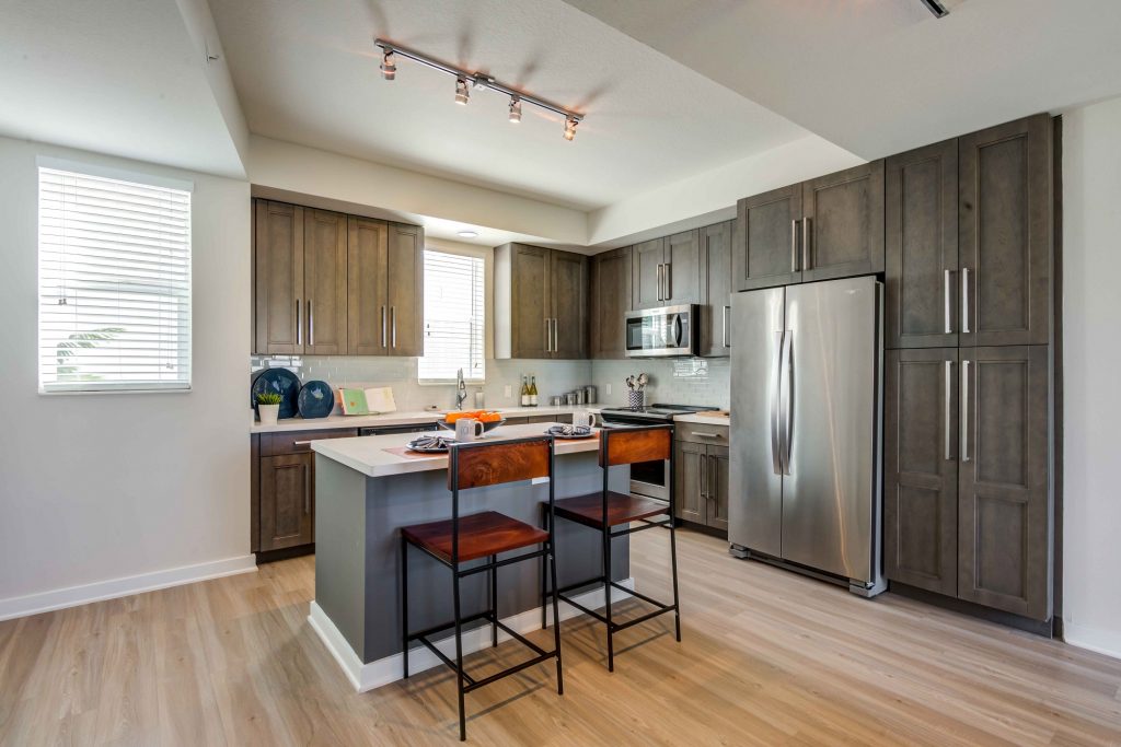 Kitchen area with island, single sink, steel appliances, wood cabinets, and wood-style flooring