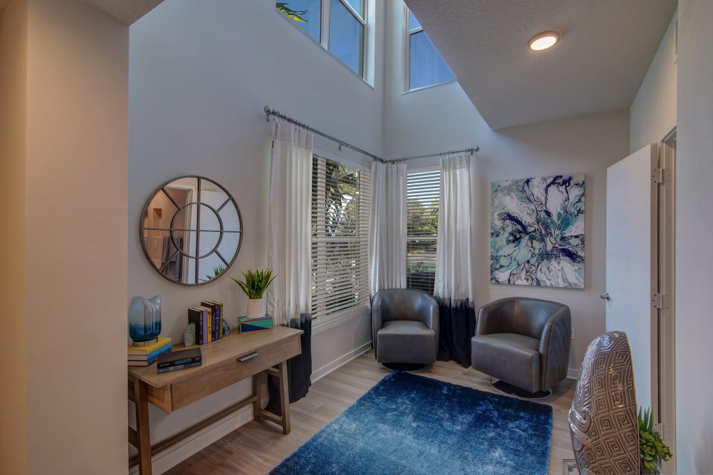 Office room area with chair seating, rug, mirror, and windows