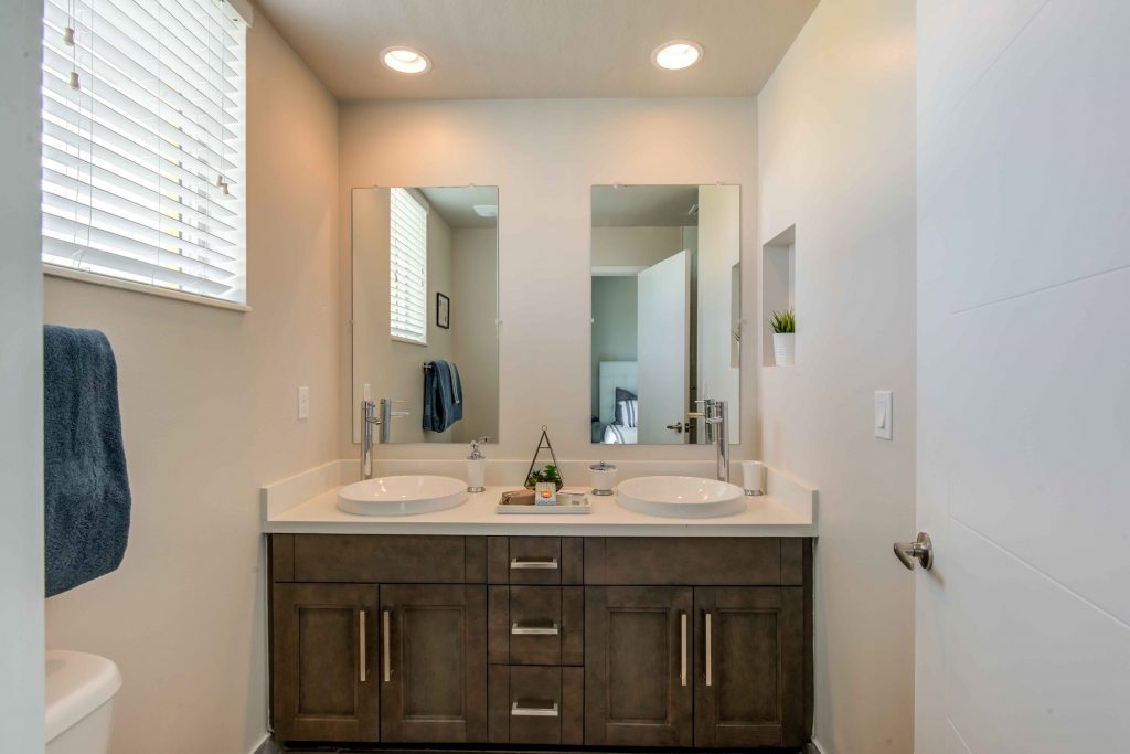 Bathroom with dual mirrors, dual sinks, window, and wood-style flooring