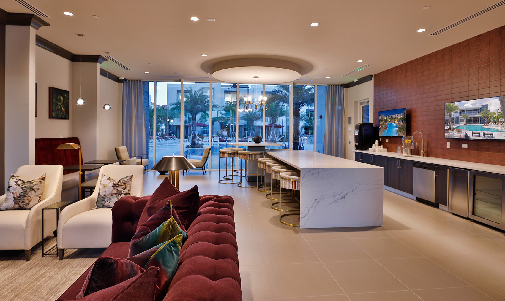 interior clubhouse area with table and bar seating, large tv, decor, and decorative lighting with view of the coffee bar