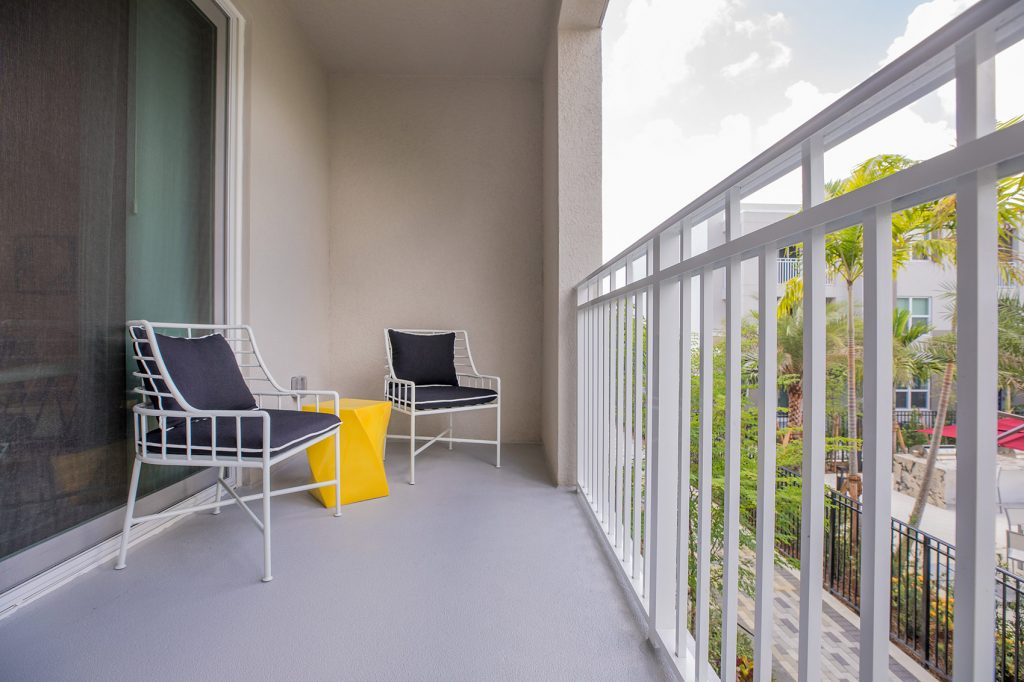 Balcony with chairs and view overlooking outdoor swimming pool area