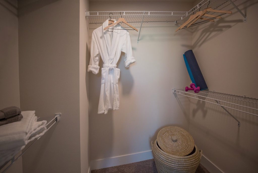 Closet with bath robe, yoga mat, clothes basket, hangers, and towels