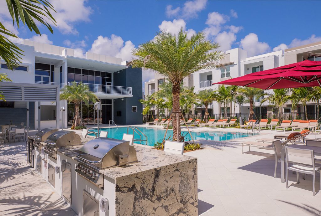 outdoor deck area with shaded seating, swimming pool, and tropical landscaping