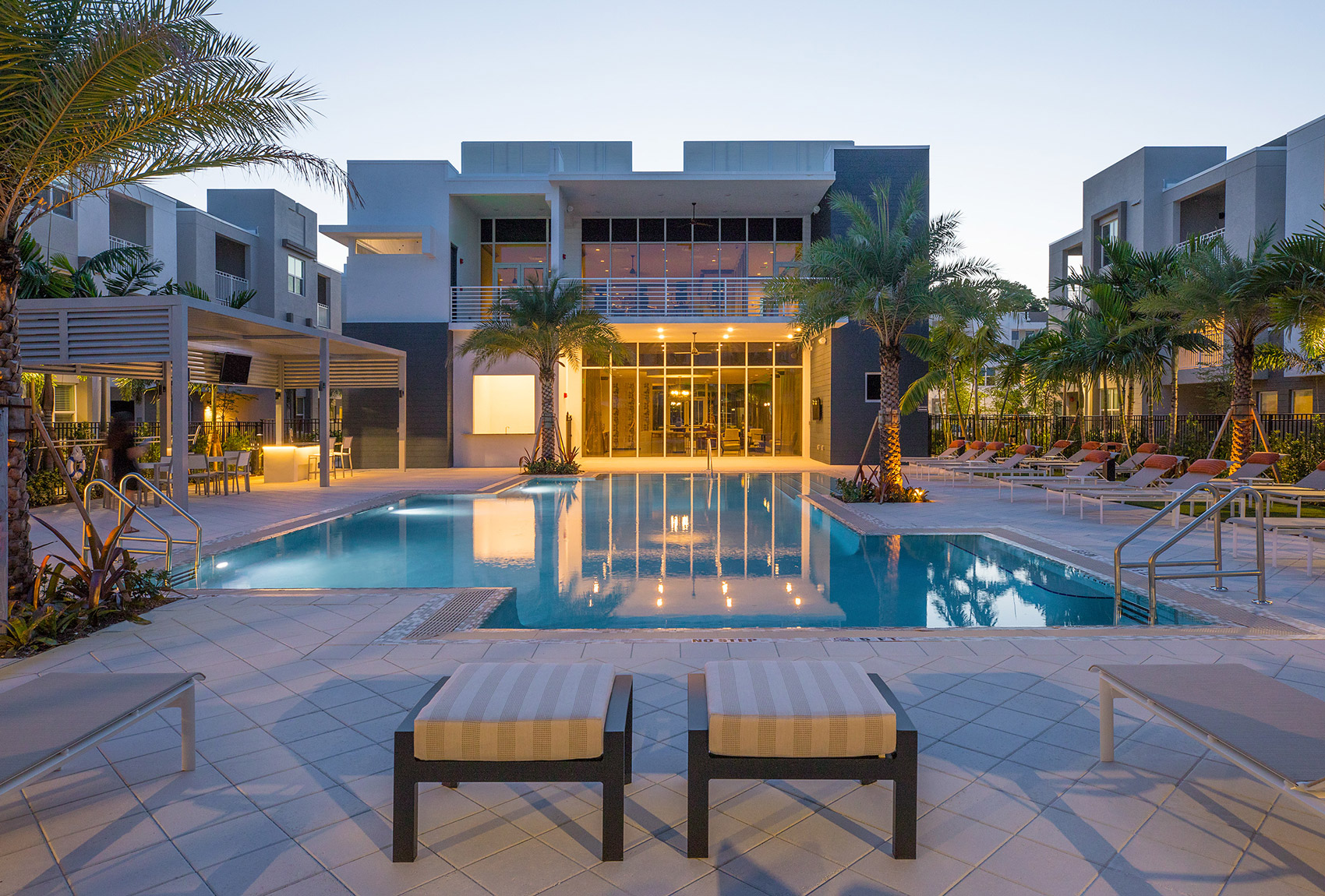 outdoor deck area with shaded seating, swimming pool, and tropical landscaping